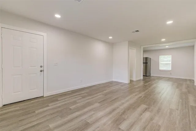 an empty room with wooden floor and window