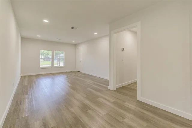 an empty room with wooden floor and window