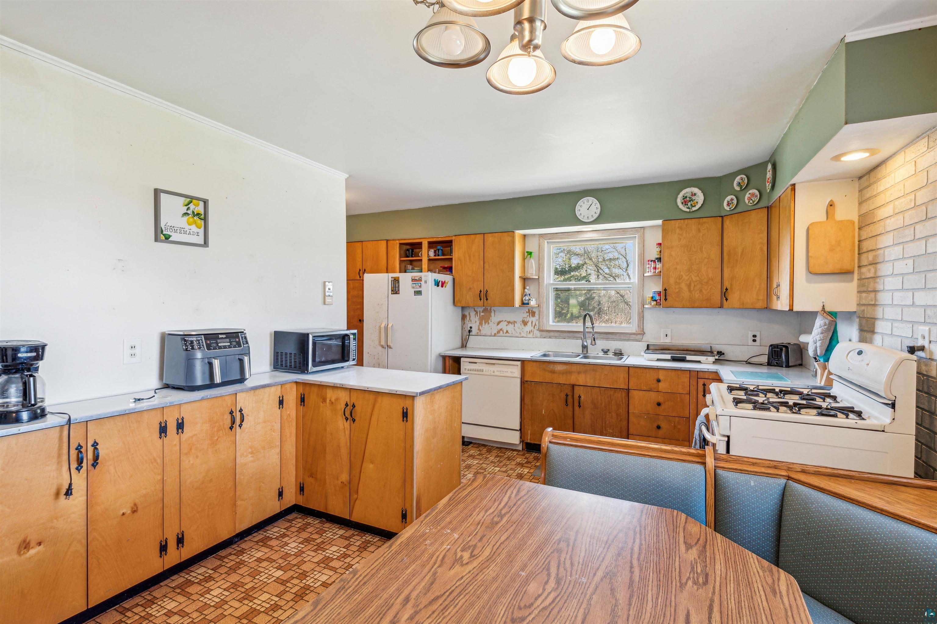 8920 School Road Port Wing, WI 54865 - Photo 11 of 27 Kitchen featuring open shelves, white appliances, light countertops, a sink, and a notable chandelier