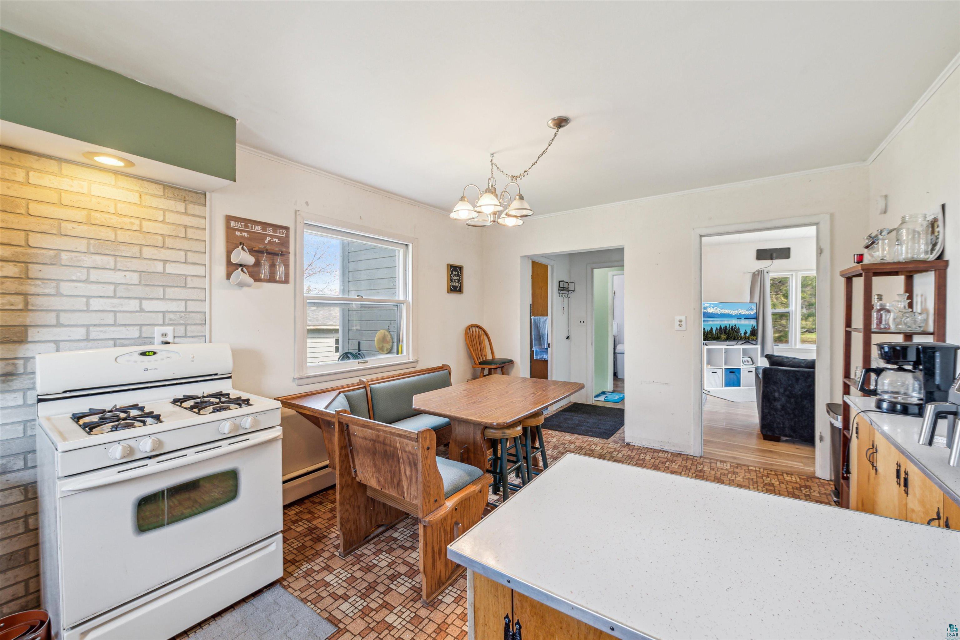 8920 School Road Port Wing, WI 54865 - Photo 13 of 27 Kitchen with a notable chandelier, white gas range oven, a healthy amount of sunlight, and baseboard heating