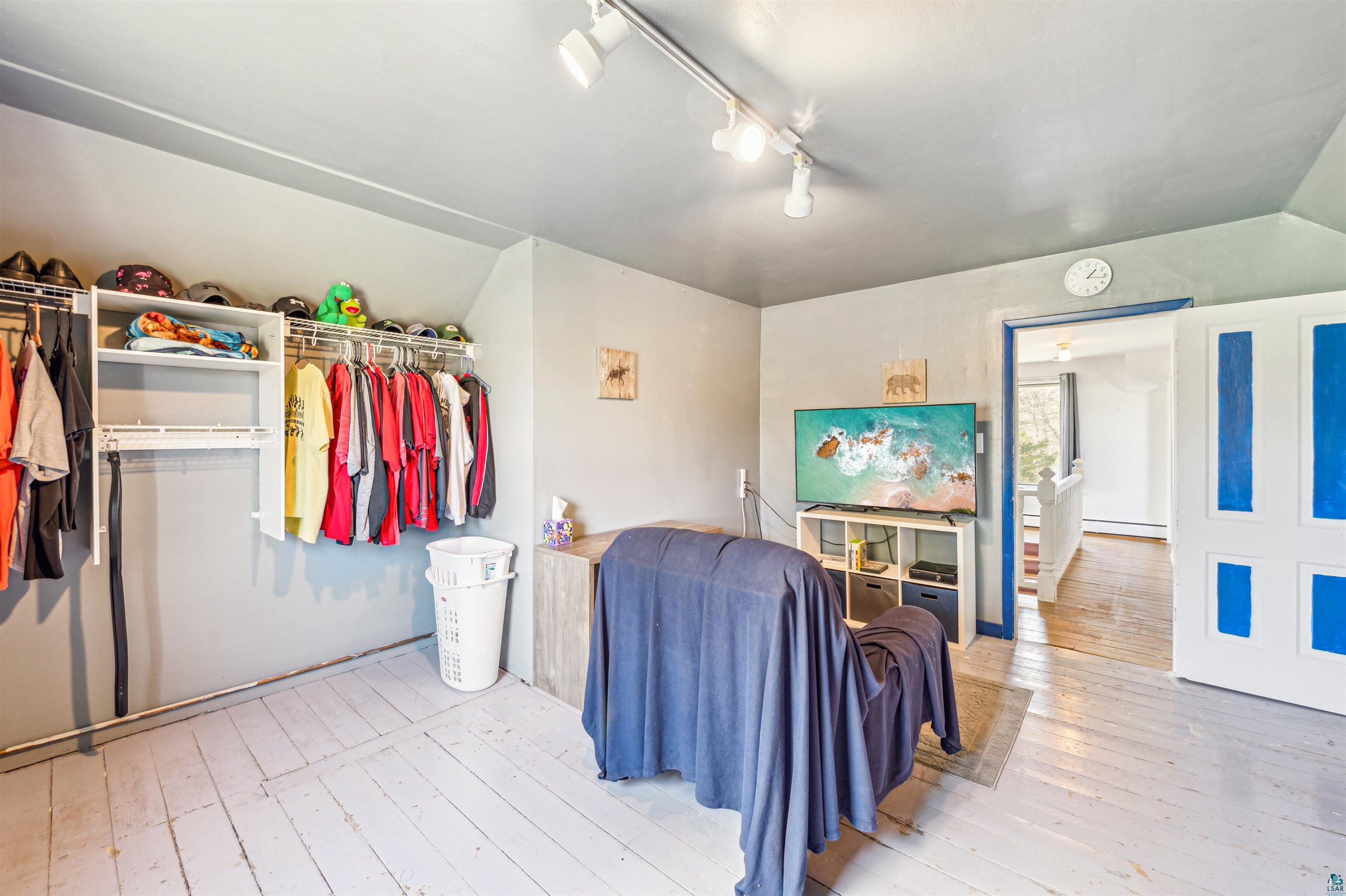 8920 School Road Port Wing, WI 54865 - Photo 18 of 27 Bedroom featuring track lighting, lofted ceiling, baseboard heating, and hardwood / wood-style flooring