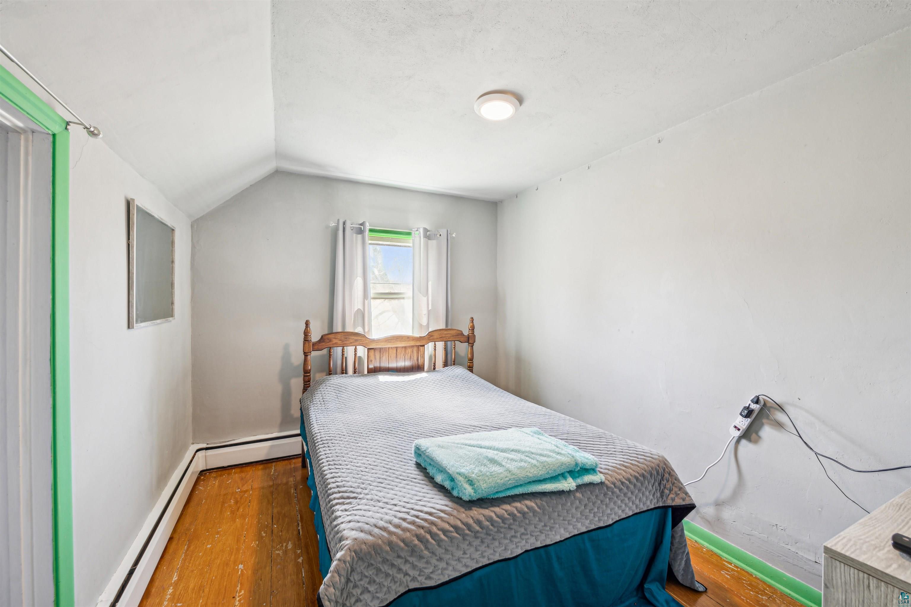 8920 School Road Port Wing, WI 54865 - Photo 22 of 27 Bedroom with baseboards, wood finished floors, lofted ceiling, and a baseboard radiator