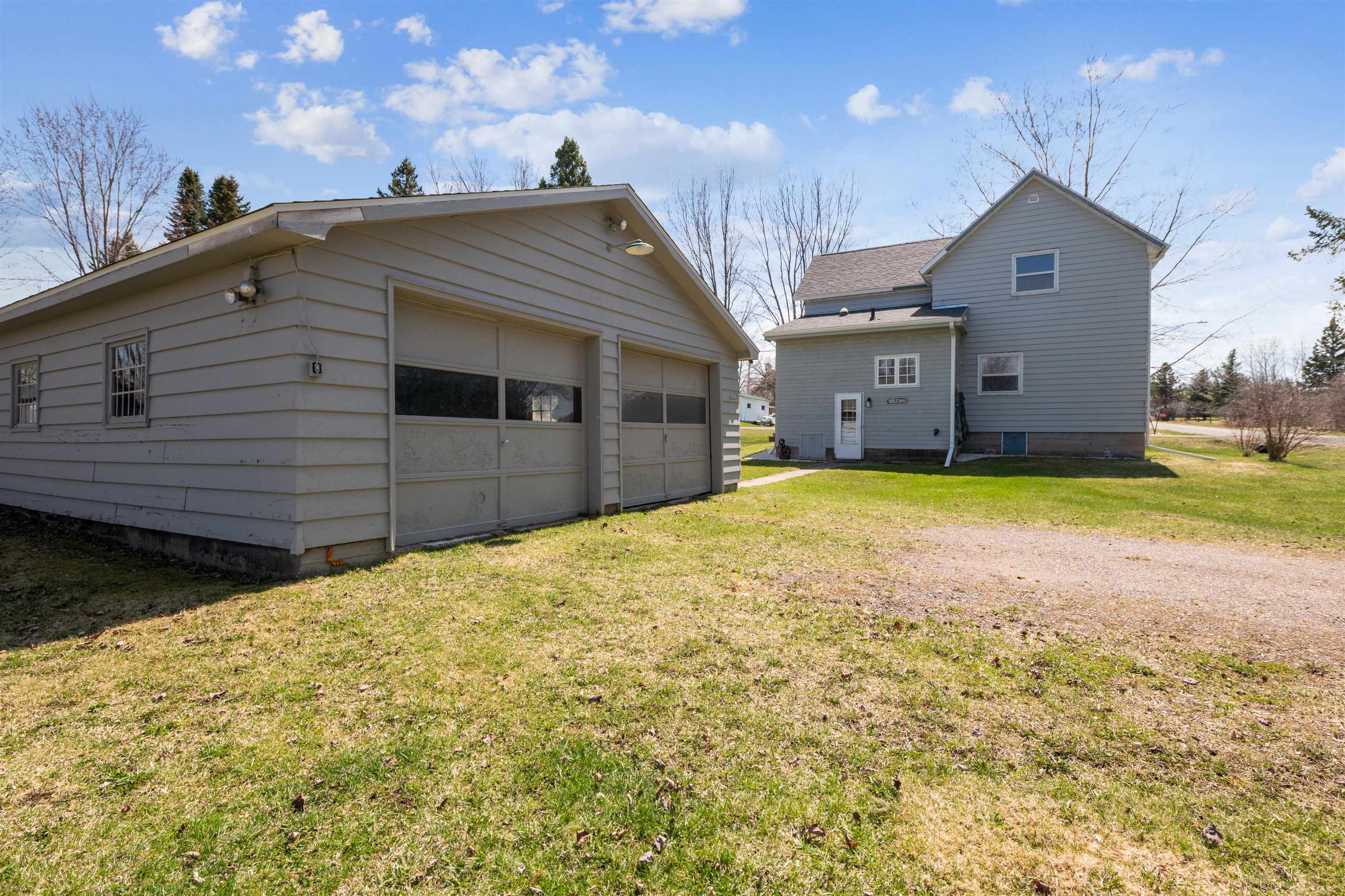 8920 School Road Port Wing, WI 54865 - Photo 25 of 27 Exterior space with a lawn, a shingled roof, an outdoor structure, and a garage