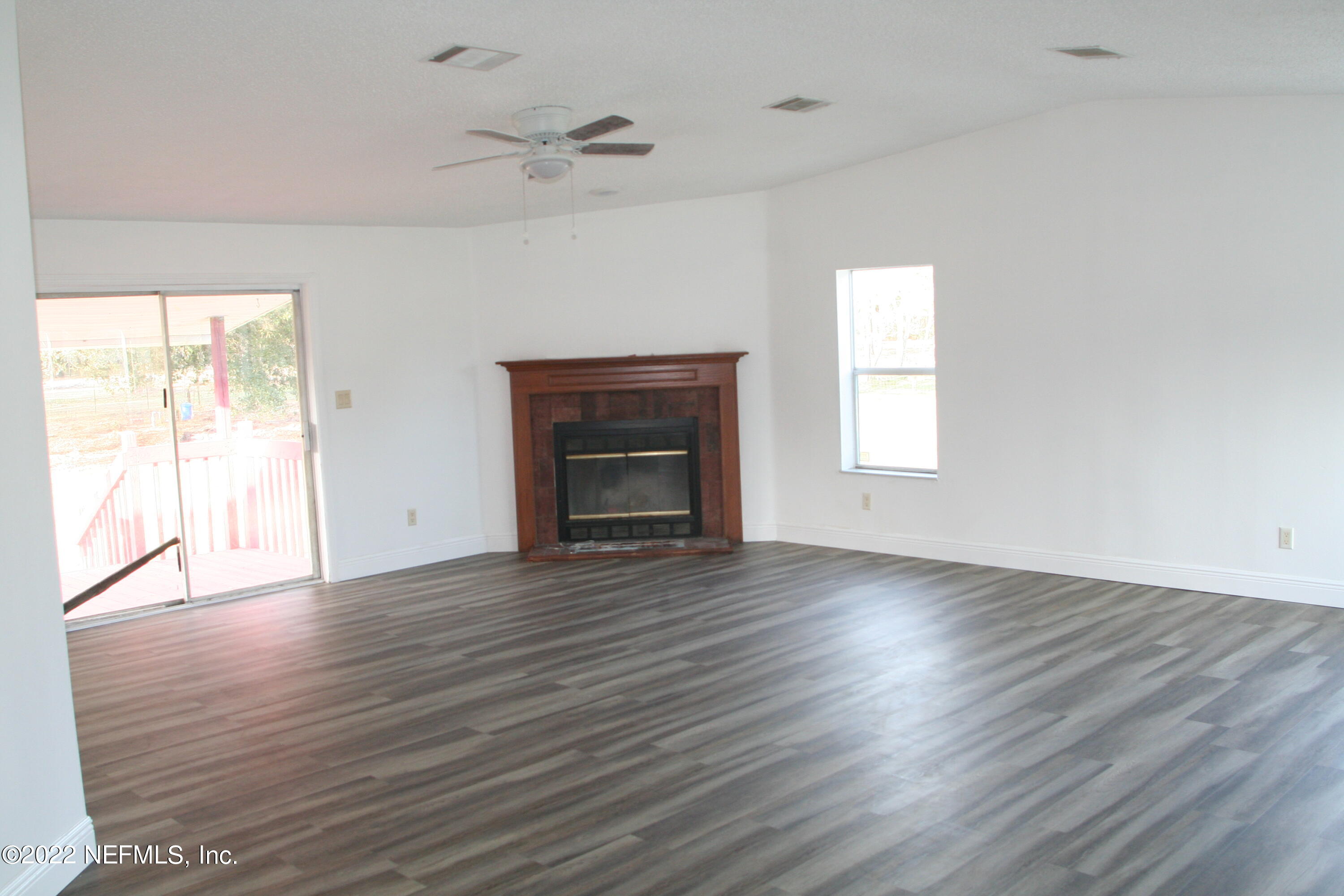 45657 Bismark Road Callahan, FL 32011 - Photo 11 of 21 an empty room with wooden floor fireplace and windows