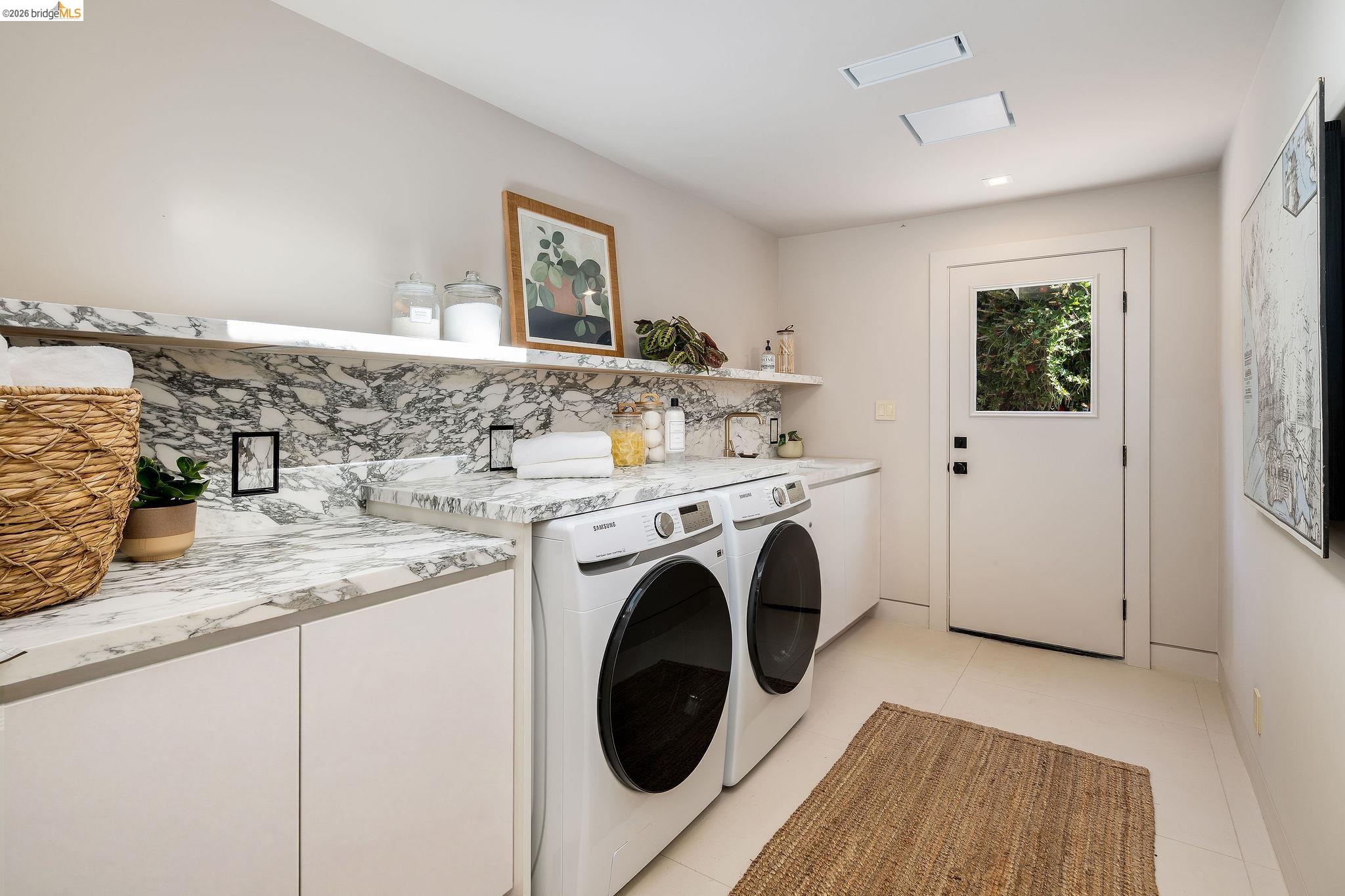 5645 Bacon Road Oakland, CA 94619 - Photo 40 of 94 Laundry space featuring a patterned stone countertop and backsplash, white cabinetry, and light-colored flooring
