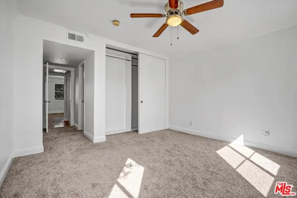 an empty room with closet and a chandelier fan
