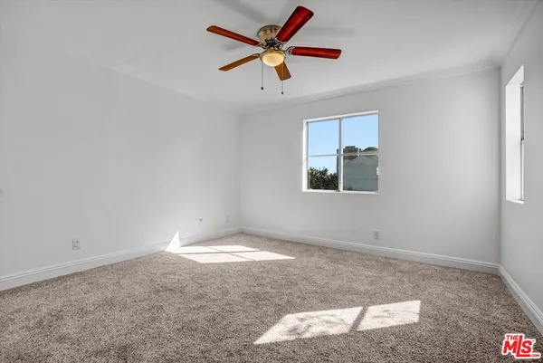 an empty room with windows and fan