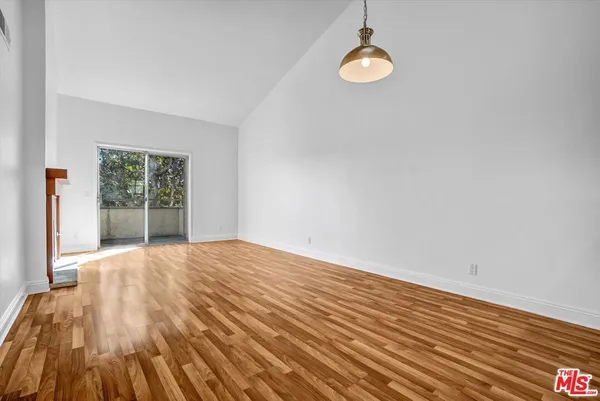 a view of an empty room with wooden floor and windows