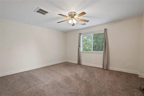 an empty room with windows and fan