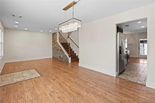 a view of a hallway with wooden floor and a chandelier