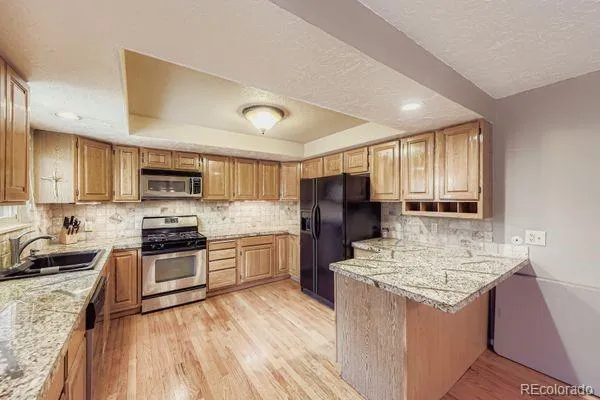 a kitchen with stainless steel appliances granite countertop a refrigerator stove microwave and sink