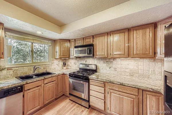 a kitchen with granite countertop a sink stainless steel appliances and cabinets