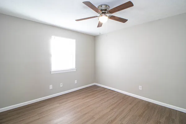 an empty room with wooden floor and windows