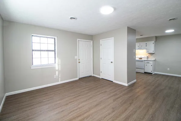 an empty room with wooden floor cabinet and windows