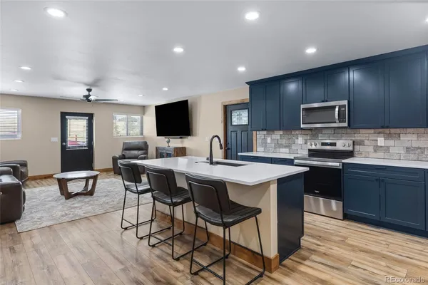 a kitchen with stainless steel appliances granite countertop wooden cabinets a refrigerator a stove a sink and a oven with wooden floor