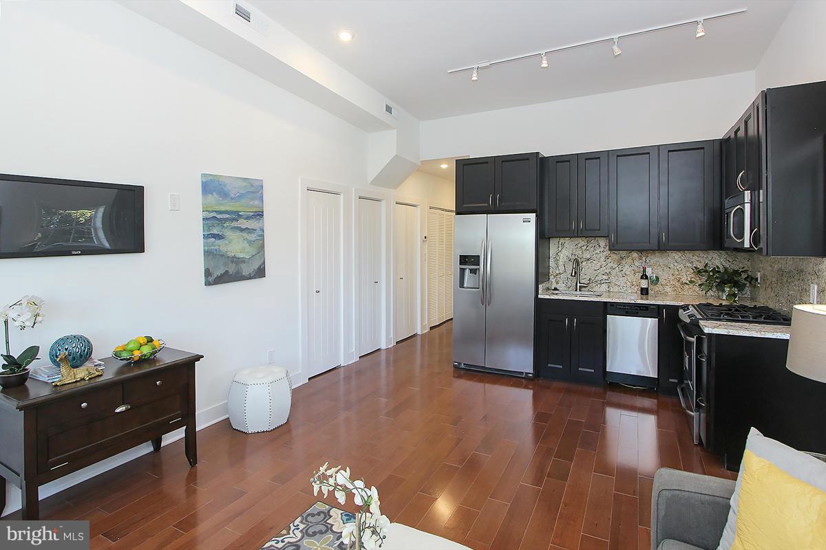 222 20th Street Northeast, Unit 1 Washington, DC 20002 - Photo 6 of 22 a kitchen with stainless steel appliances kitchen island granite countertop a refrigerator a stove and a wooden floors