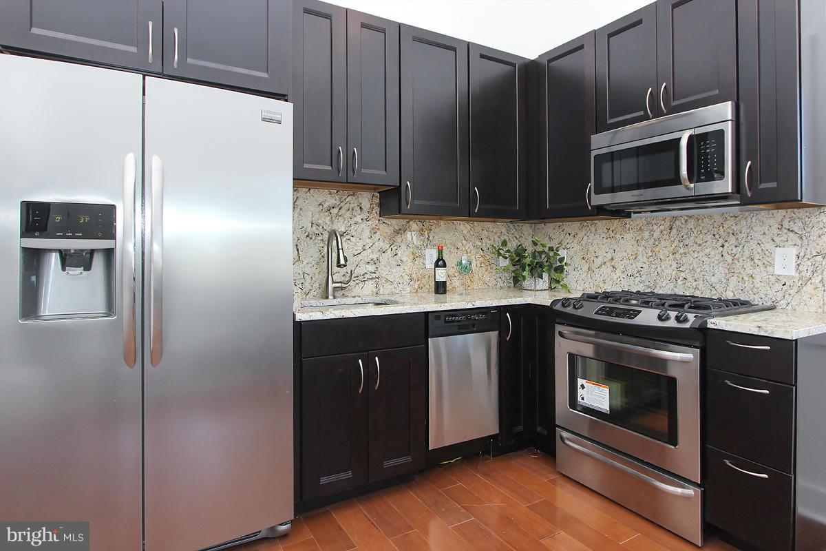 222 20th Street Northeast, Unit 1 Washington, DC 20002 - Photo 8 of 22 a kitchen with granite countertop stainless steel appliances and wooden cabinets
