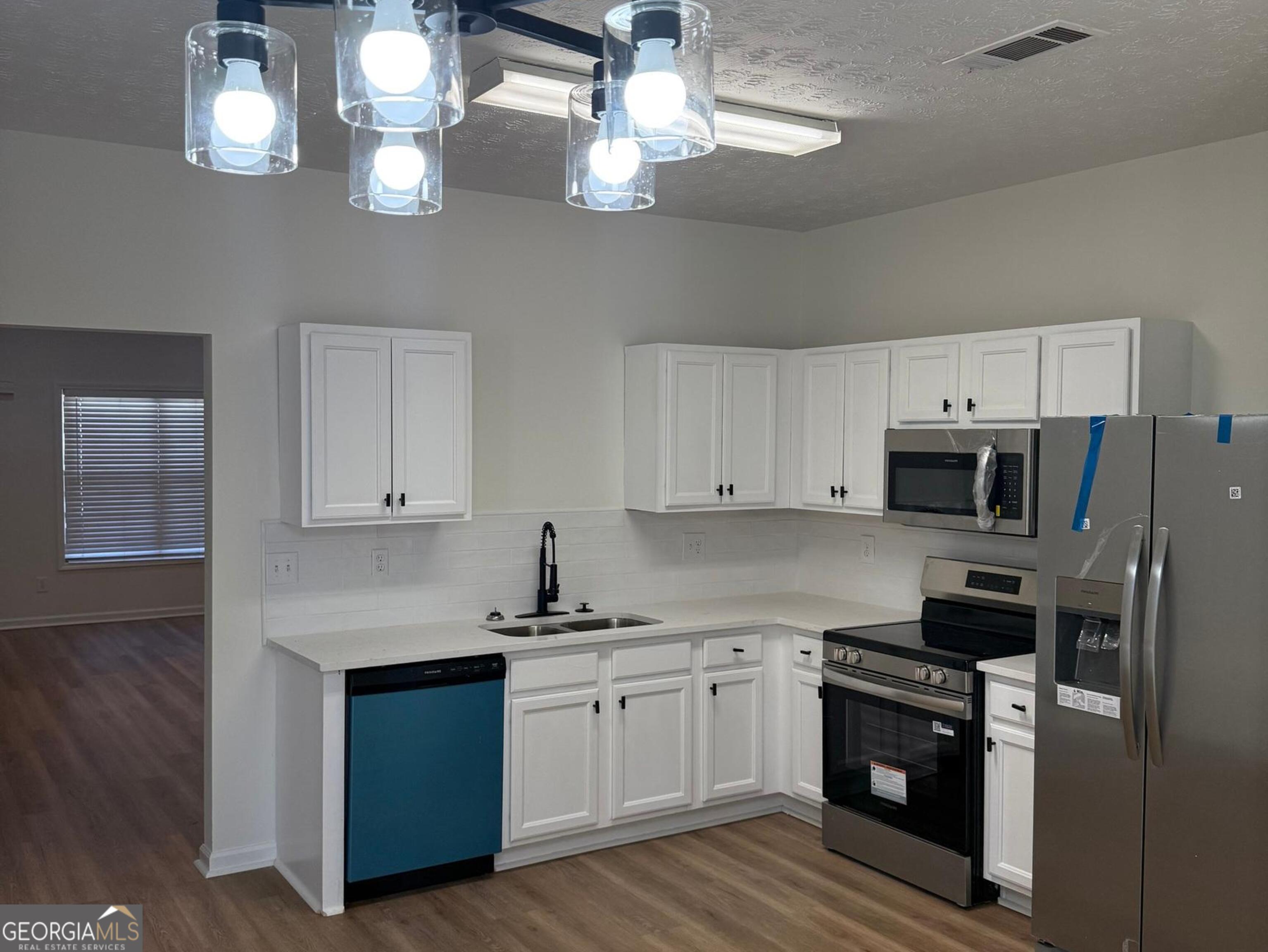 5471 Walnut Lane Lithonia, GA 30038 - Photo 13 of 40 a kitchen with cabinets stainless steel appliances and wooden floor