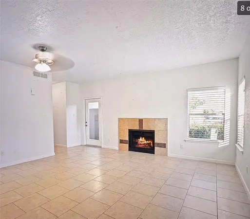 an empty room with windows and fireplace