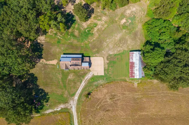 an aerial view of residential houses with outdoor space and trees