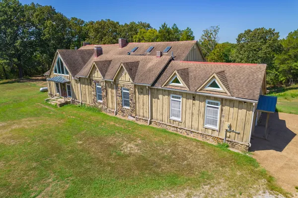 a view of a big house with a big yard and large trees