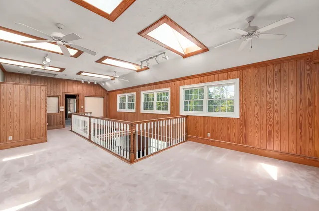 an empty room with wooden floor fan and windows