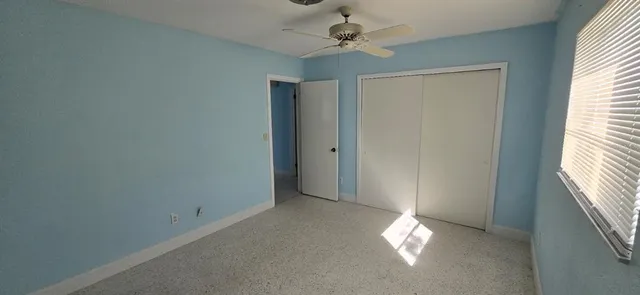 an empty room with windows and fan