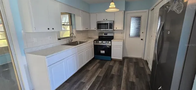 a kitchen with white cabinets sink and stainless steel appliances