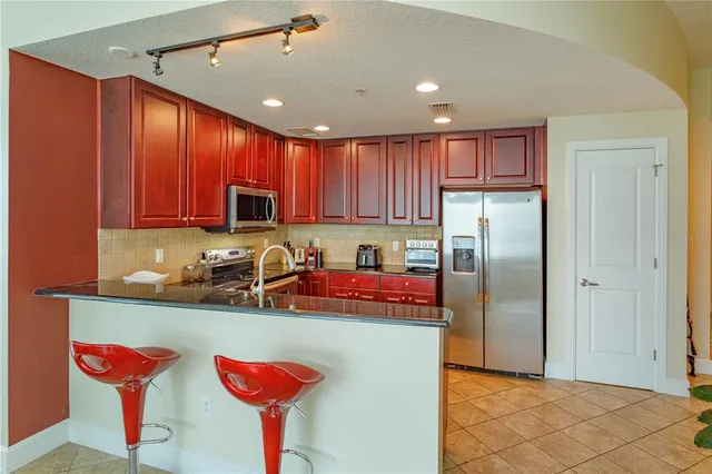 a kitchen with stainless steel appliances granite countertop a refrigerator a sink and a stove