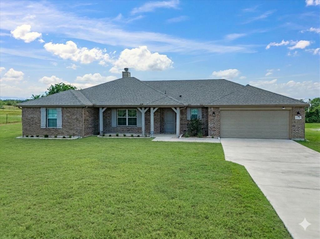 129 Springwood Ranch Loop Springtown, TX 76082 - Photo 2 of 26 Brick exterior home featuring a covered front porch with decorative columns, a two-car garage, and a concrete driveway