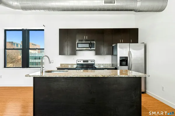 a kitchen with granite countertop a refrigerator and a stove top oven