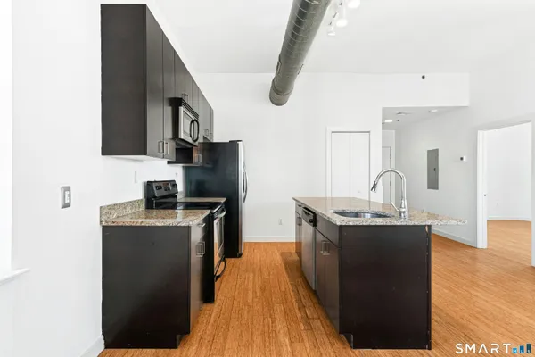 a kitchen with kitchen island a sink dishwasher a stove and a microwave oven with wooden floor