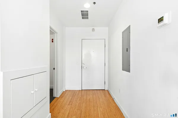 a view of an empty room with wooden floor and windows