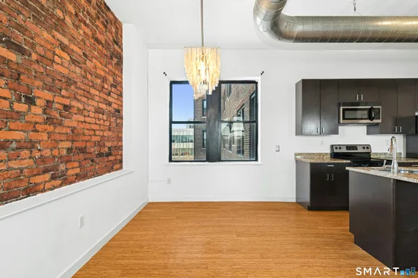 a kitchen with stainless steel appliances kitchen island granite countertop a refrigerator a stove top oven a sink with granite countertops and cabinets