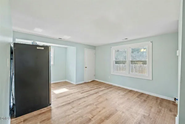 a view of an empty room with window and wooden floor