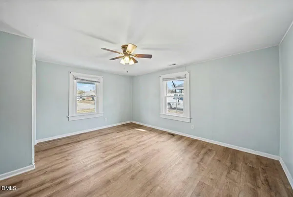 a view of an empty room with a window and wooden floor