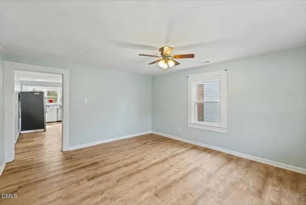 a view of an empty room with a window and wooden floor