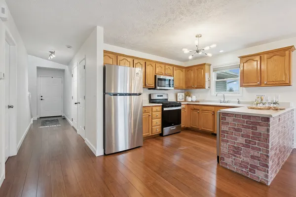 a kitchen with stainless steel appliances granite countertop a refrigerator a sink dishwasher a stove with wooden floor and cabinets