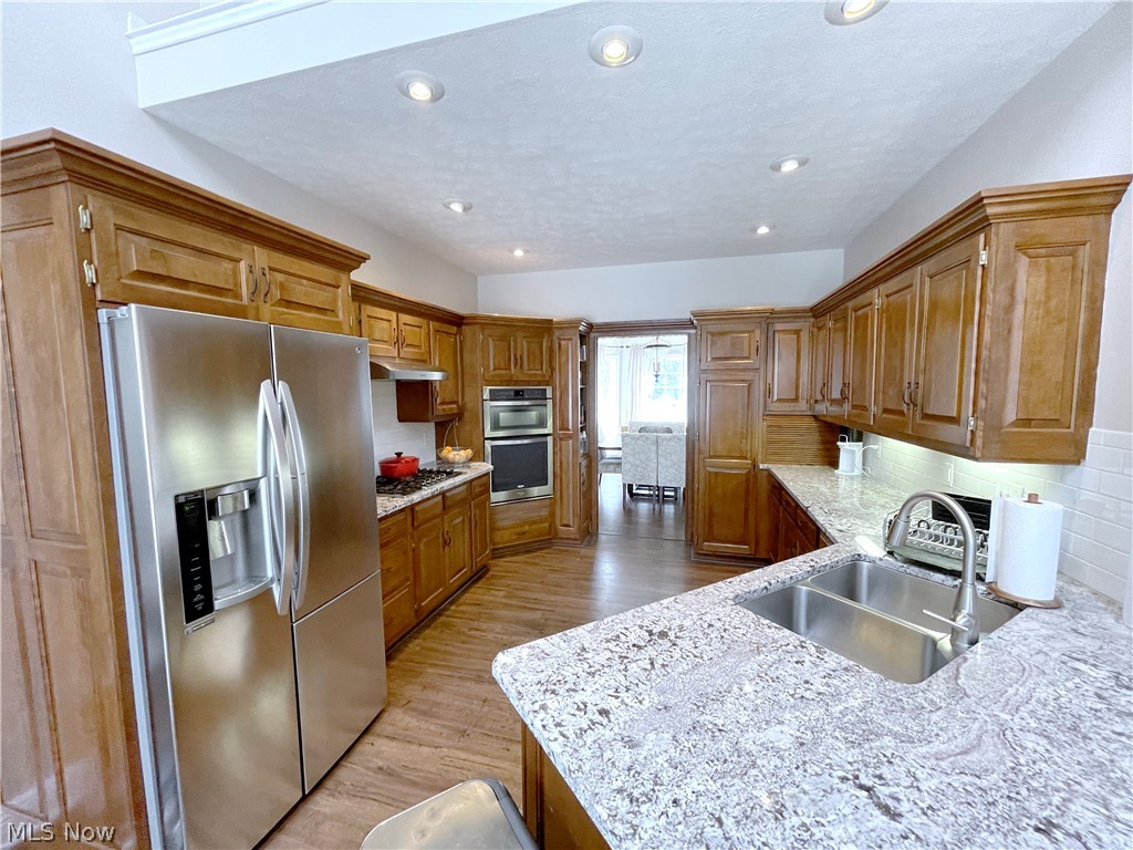 718 Sunridge Road Fairlawn, OH 44333 - Photo 7 of 49 Kitchen with sink, appliances with stainless steel finishes, backsplash, light hardwood / wood-style floors, and light granite countertops