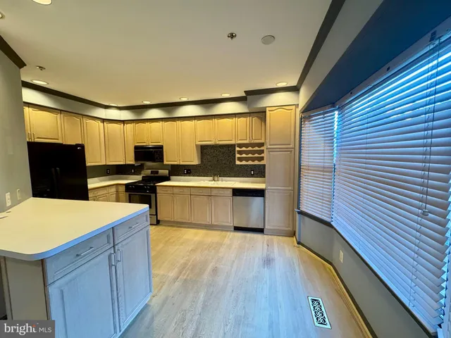a kitchen with stainless steel appliances wooden floor sink and wooden cabinets