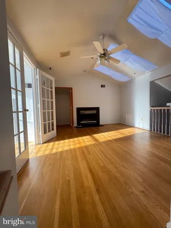 a view of an empty room with window and wooden floor