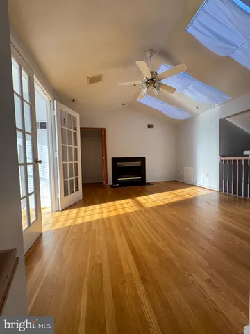 a view of an empty room with window and wooden floor