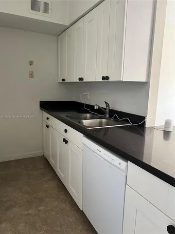a kitchen with granite countertop white cabinets and sink