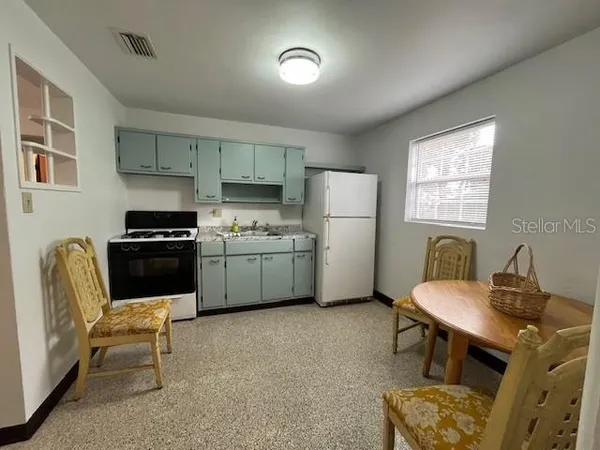 a kitchen with furniture a refrigerator and a stove top oven