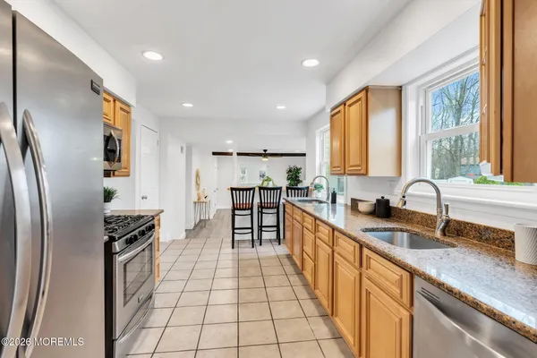 a kitchen with granite countertop a refrigerator a sink a stove top oven and cabinets