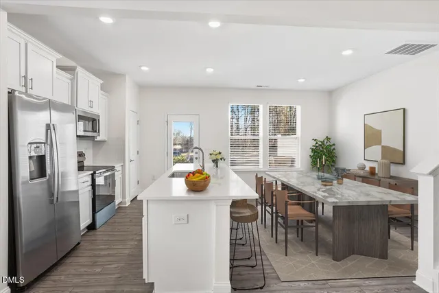a kitchen with a table chairs refrigerator and cabinets