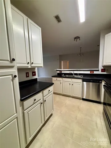 a kitchen with granite countertop a sink and white cabinets