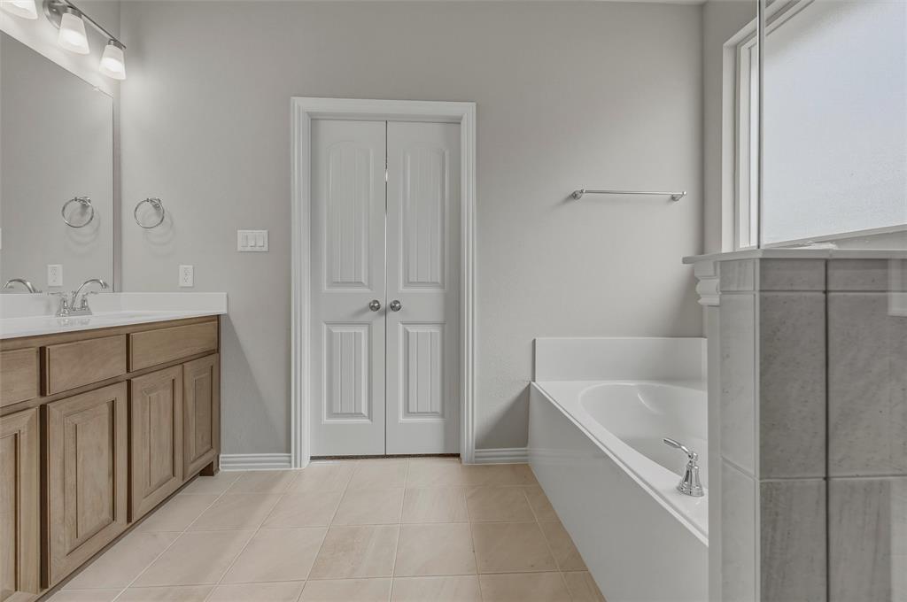 1201 Colca Drive Springtown, TX 76082 - Photo 25 of 32 Dual sink vanity with wood-finish cabinetry, tile flooring, built-in bathtub, and a shower with frosted glass