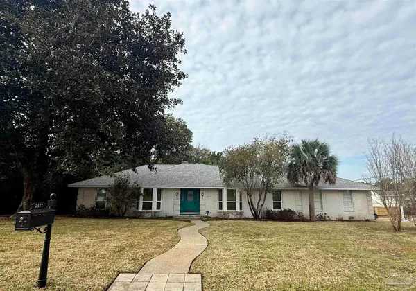 a front view of a house with a garden and tree