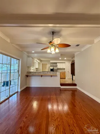 a view of a room with wooden floor kitchen view and windows